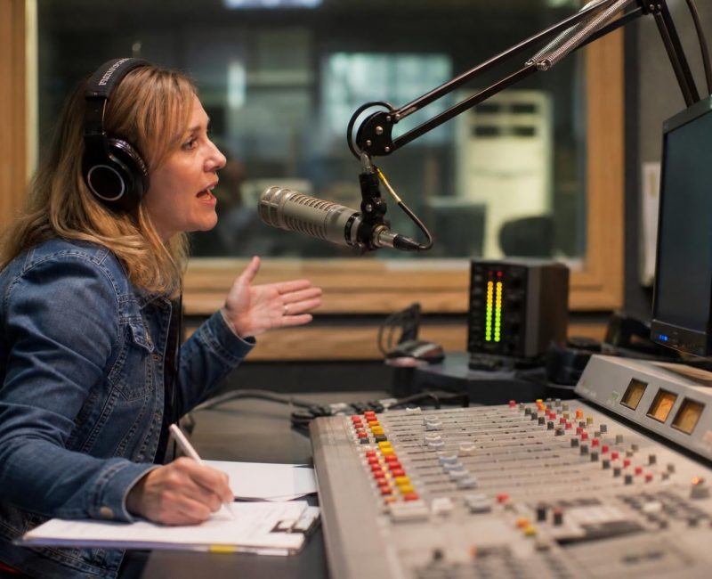 Radio host speaking on-air at local radio station broadcast console